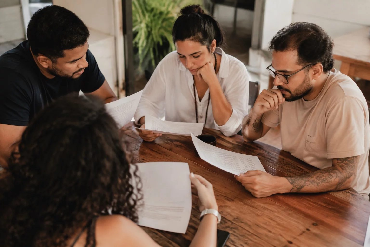 Grupo pequeno lendo páginas impressas de argumentos ao redor de uma mesa
