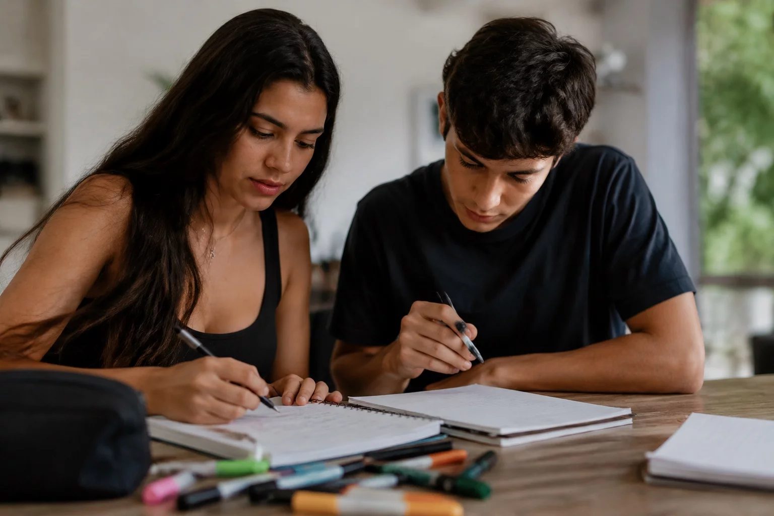 Dois estudantes preparando um debate com cadernos e marcadores